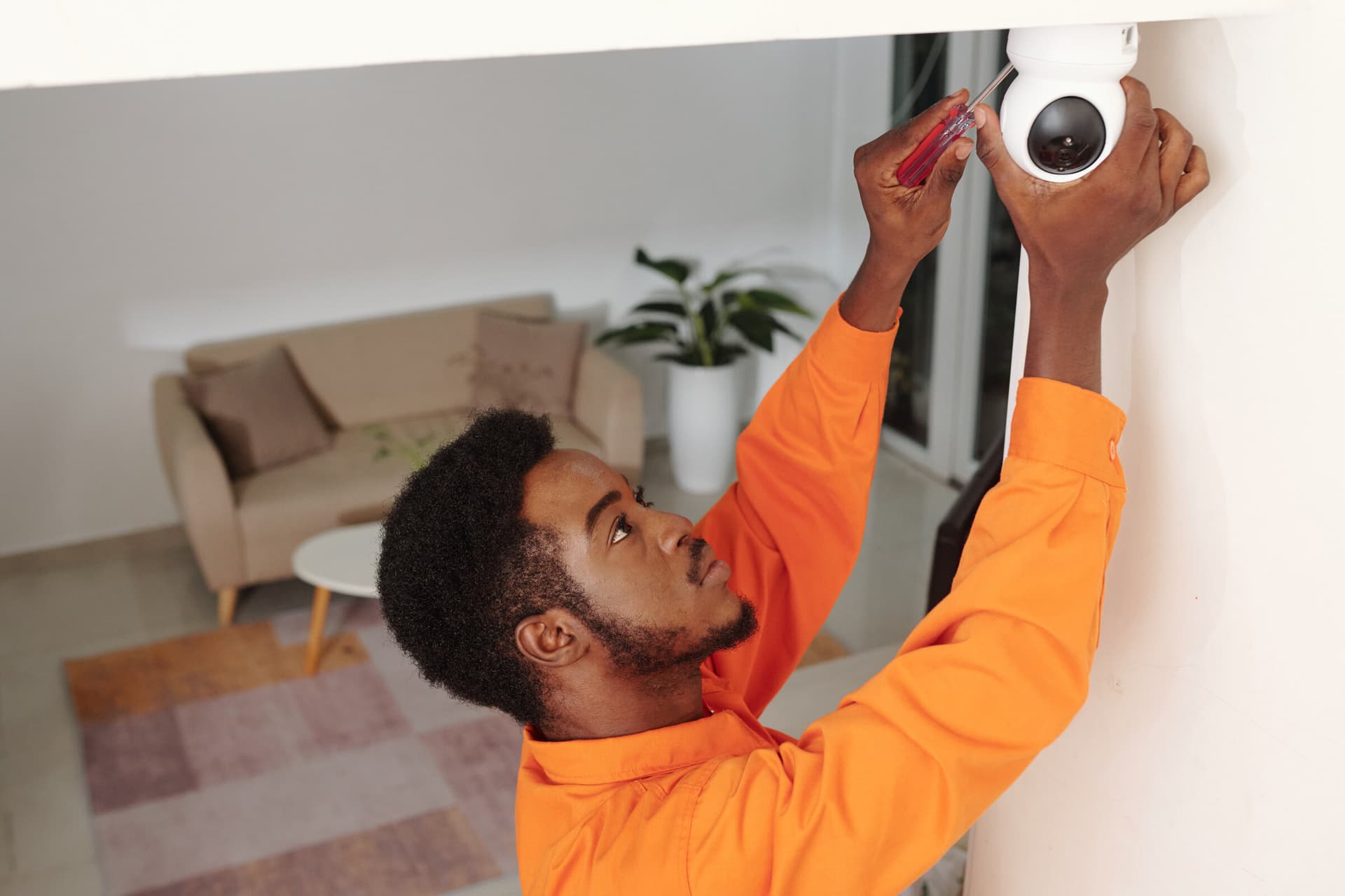Security technician installing a dome camera on an indoor ceiling